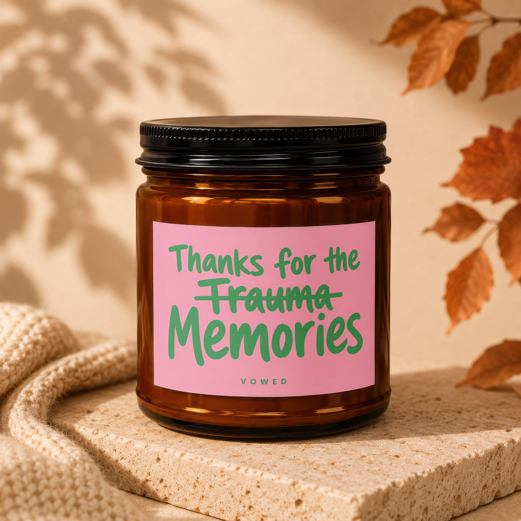 Amber jar candle with pink label reading "Thanks for the trauma memories" and "VOWED"