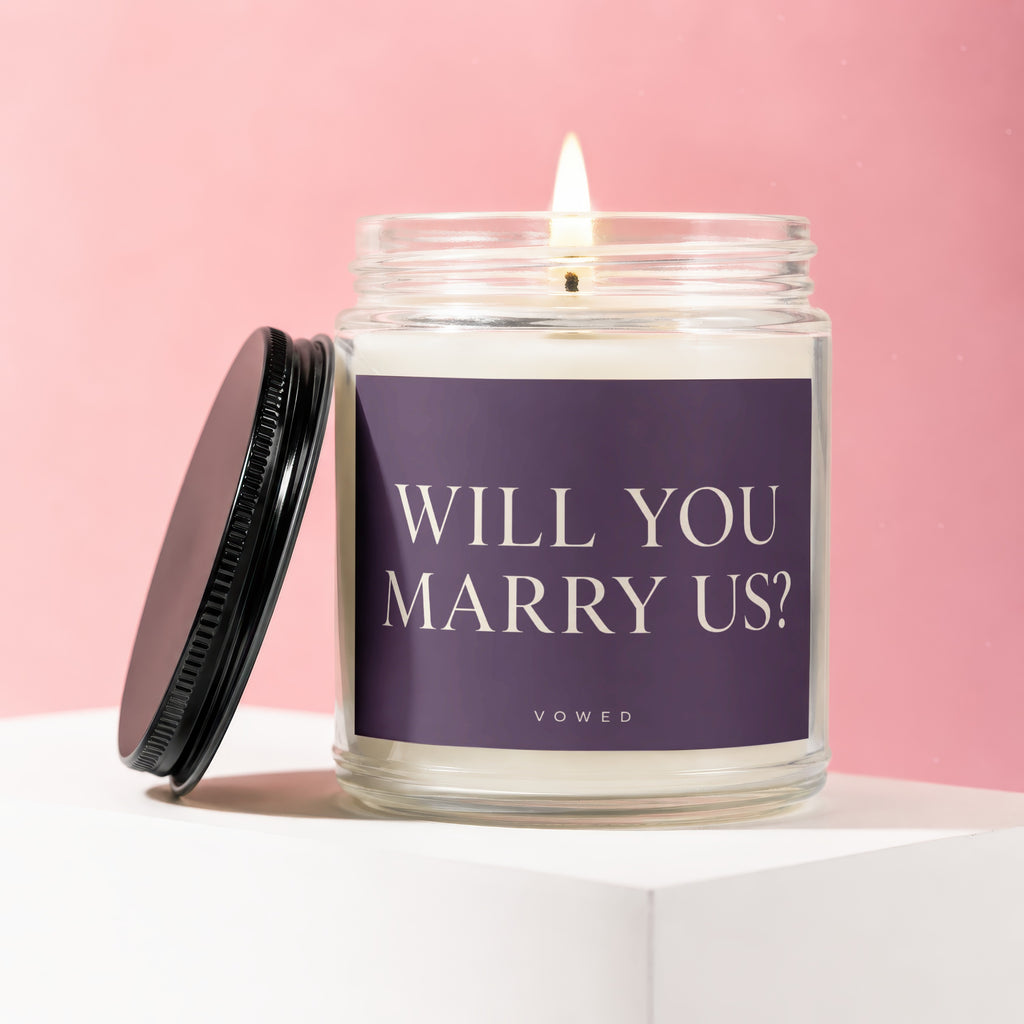 Candle with "WILL YOU MARRY US?" text on label and "VOWED" below.