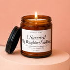 Amber glass candle with lid off, labeled "I Survived My Daughter's Wedding".