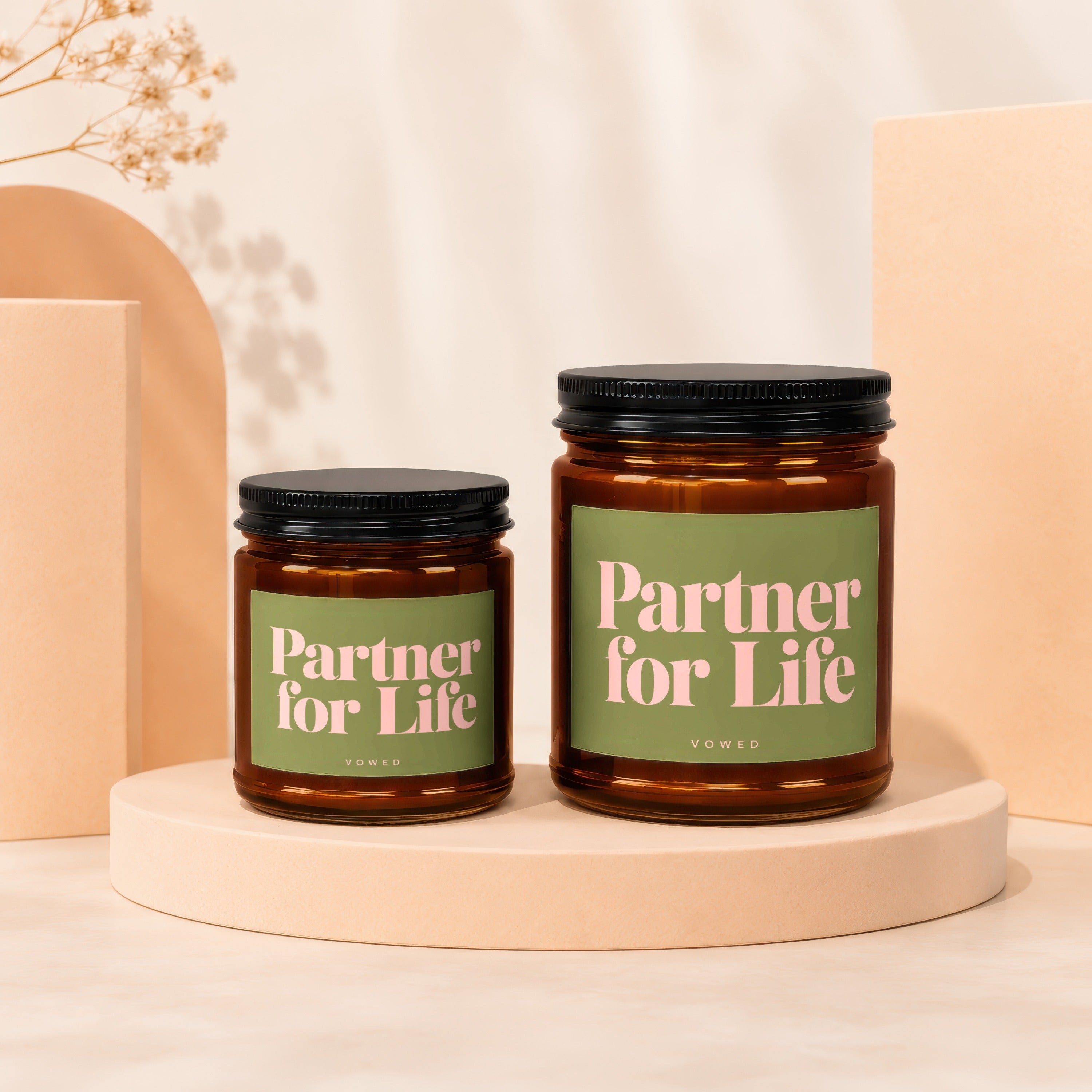 Two amber glass candles with black lids and green labels saying "Partner for Life."