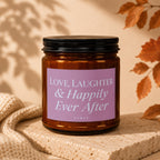 Amber jar candle with pink label reading "Love, Laughter & Happily Ever After"