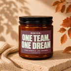 Amber jar candle with black lid reads "Roster: One Team, One Dream".