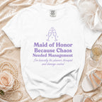 White T-shirt with purple text reading "Maid of Honor Because Chaos Needed Management" and "I'm basically the planner, therapist and damage control".