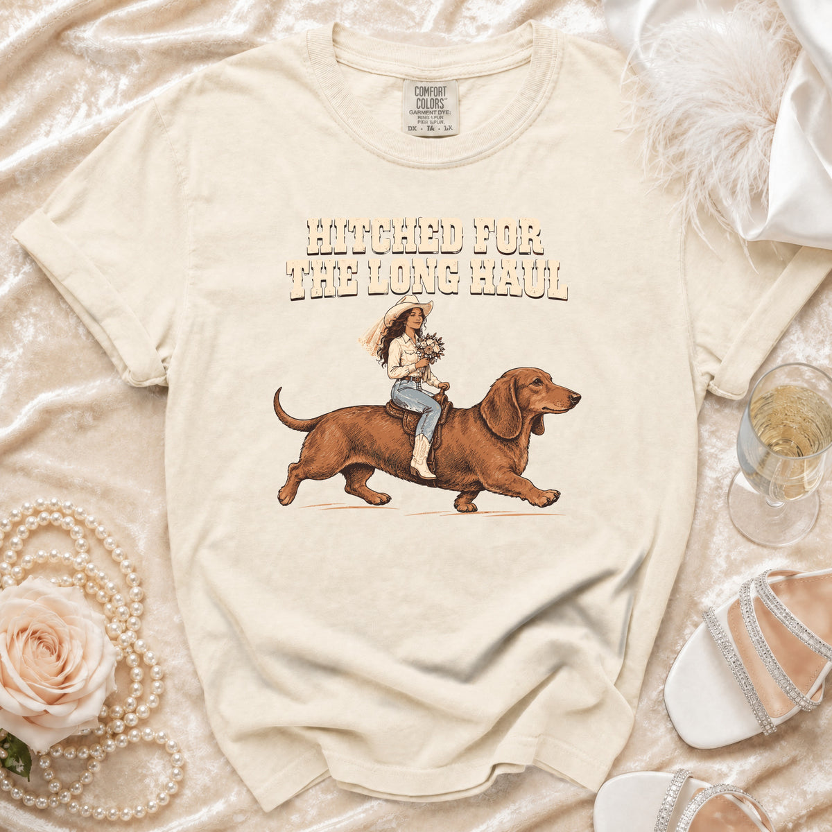 Cream t-shirt with "Hitched for the Long Haul" text and bride riding a dachshund.