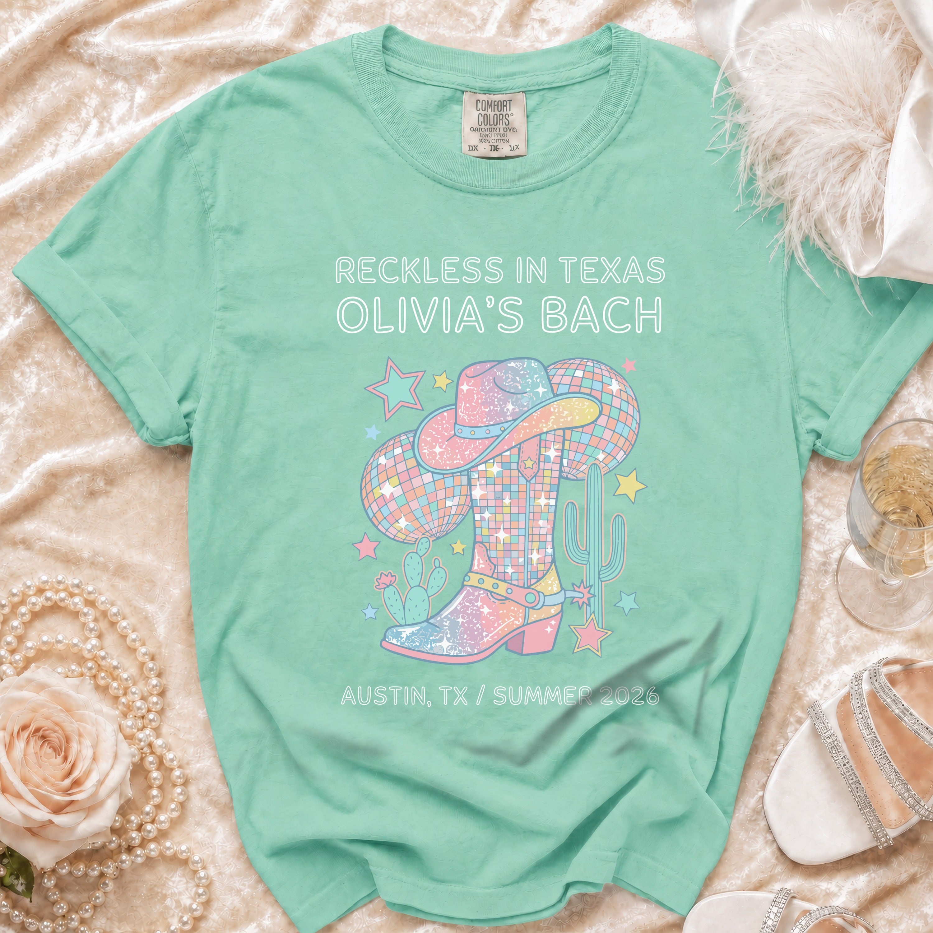 Mint green t-shirt with "Reckless in Texas Olivia's Bach" and Western design.