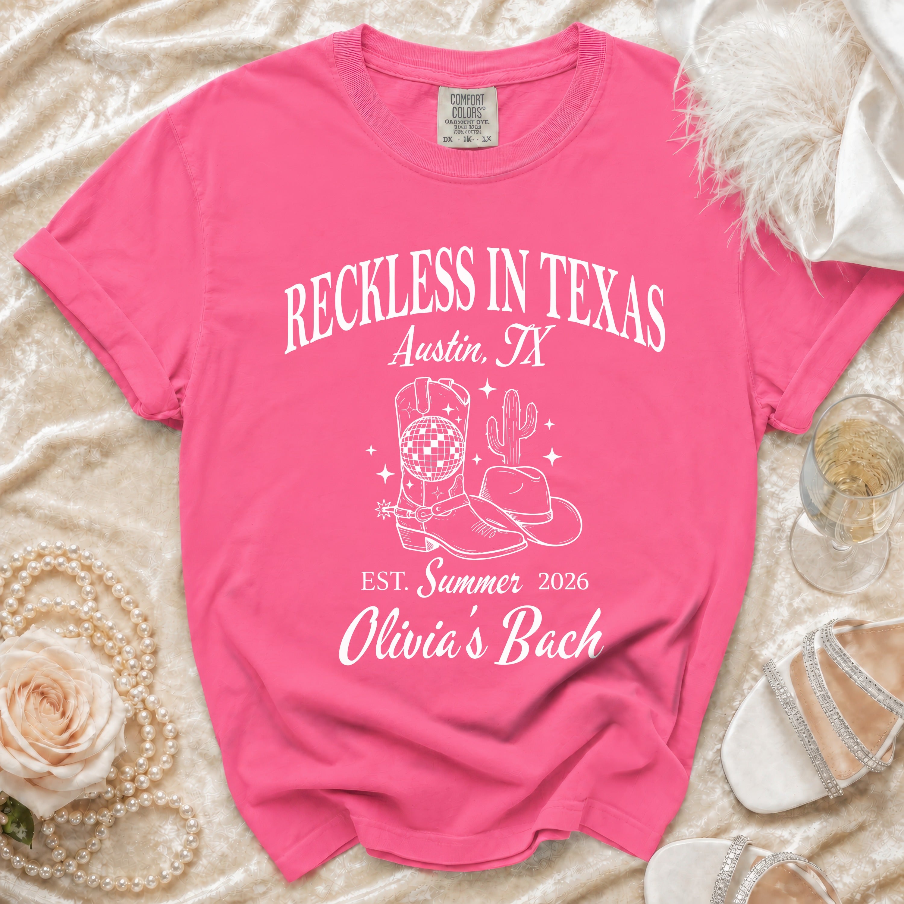 Pink t-shirt with "Reckless in Texas, Austin, TX, Est. Summer 2026, Olivia's Bach" and cowboy boot graphic.