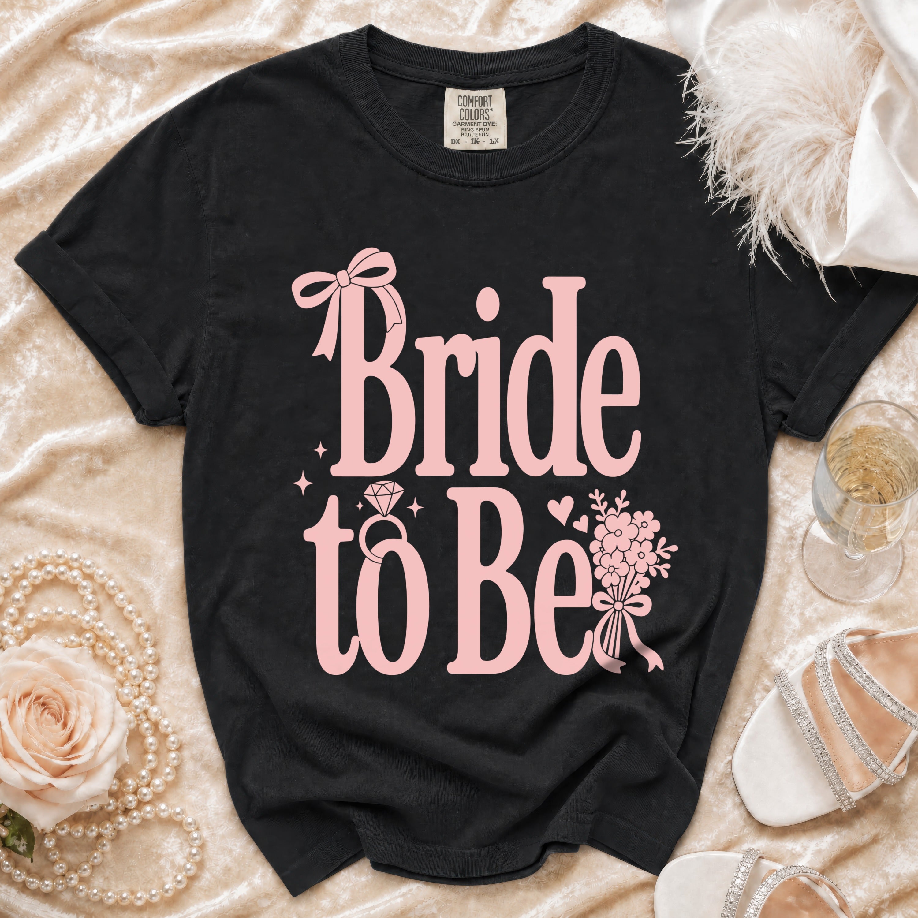 Black 'Bride to Be' t-shirt with pink text, ring, and floral accents.