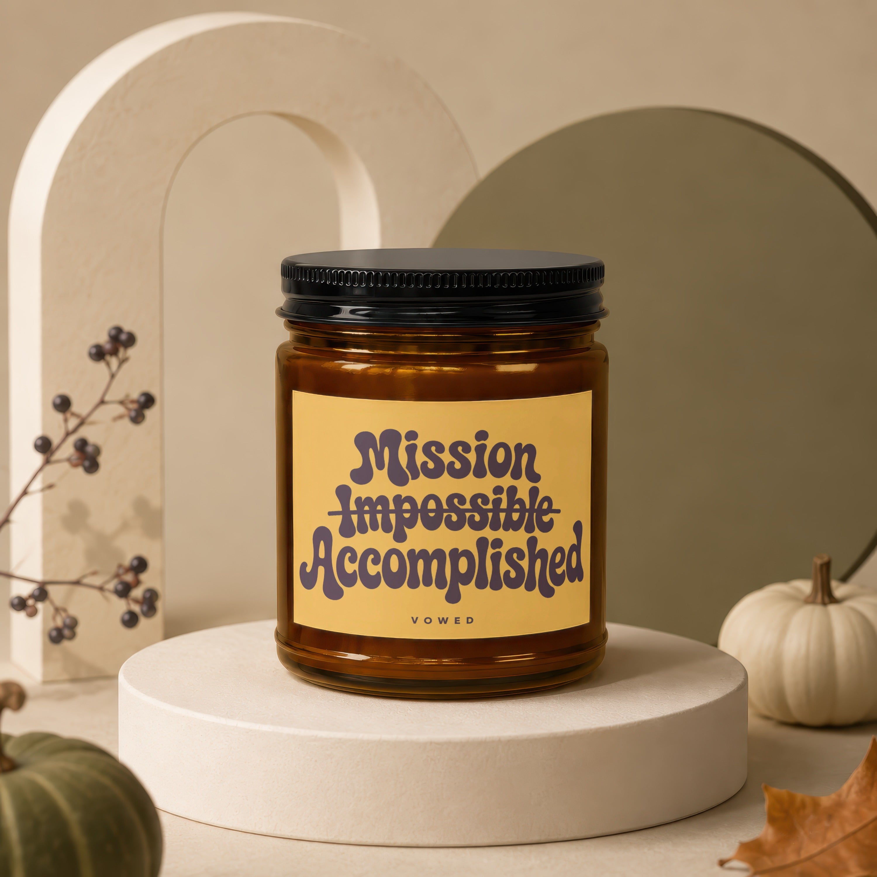 Amber candle with black lid labeled "Mission Impossible Accomplished".