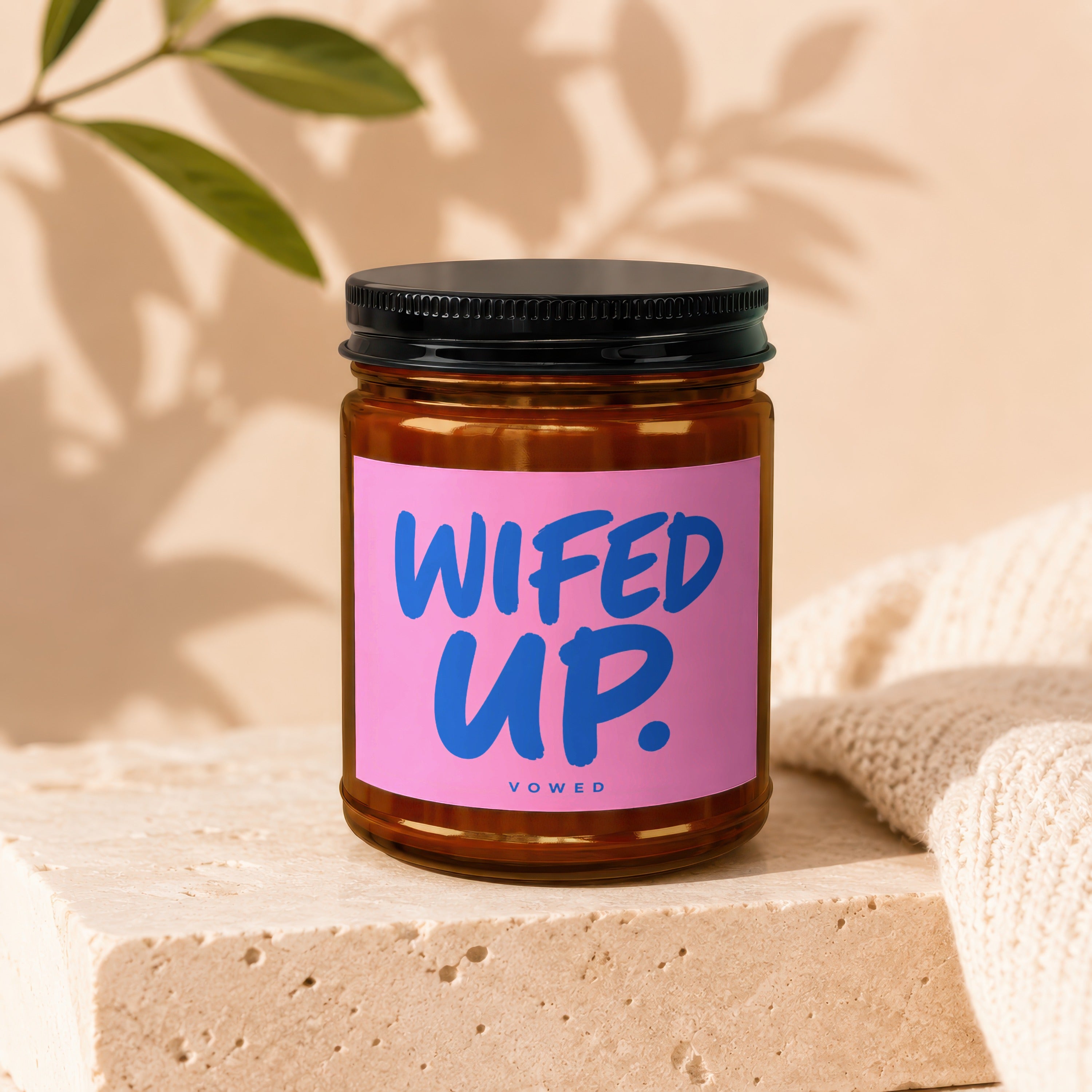 Brown glass candle in jar with pink label reading "WIFED UP." and "VOWED."
