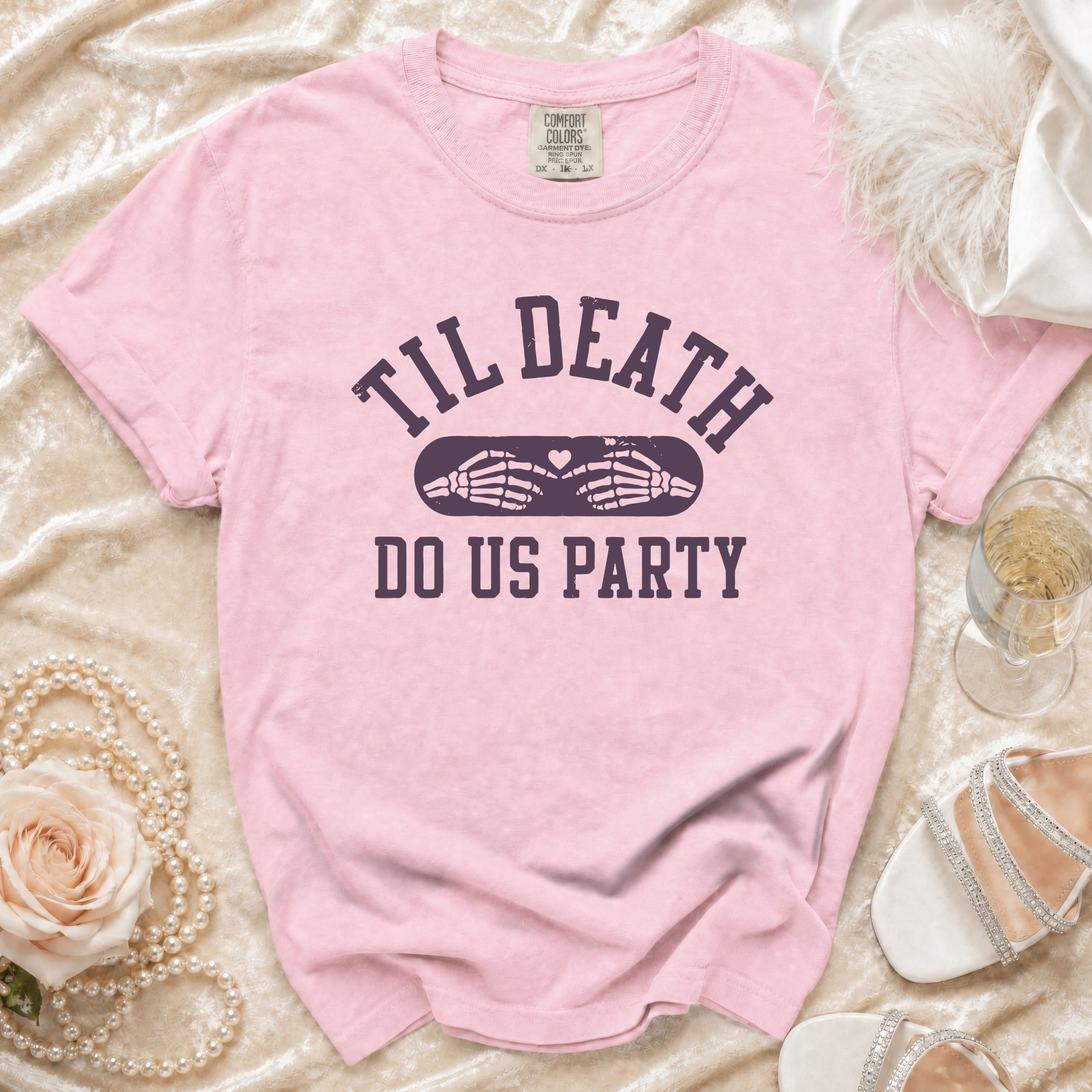 Pink t-shirt with "Til Death Do Us Party" text and skeleton hands forming a heart.