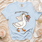 Light blue t-shirt with cartoon goose wearing a veil and holding flowers with "off to get married" text.