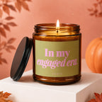 Lit amber glass candle with "In my engaged era." and "VOWED" text.