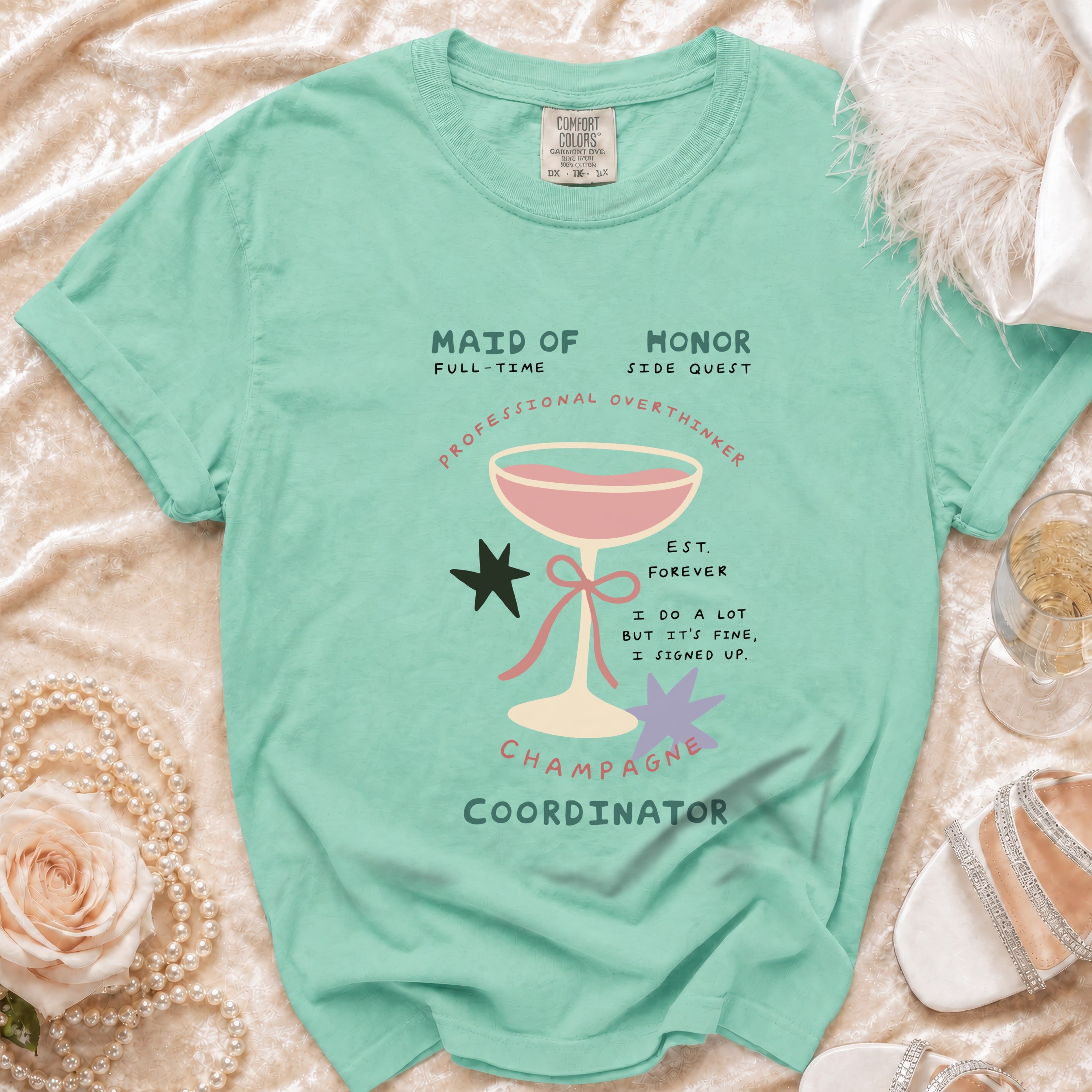 Seafoam green t-shirt with "Maid of Honor, Champagne Coordinator" text and graphics.