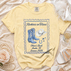Yellow t-shirt with "Reckless in Texas," boots, hat, and horseshoe graphic.