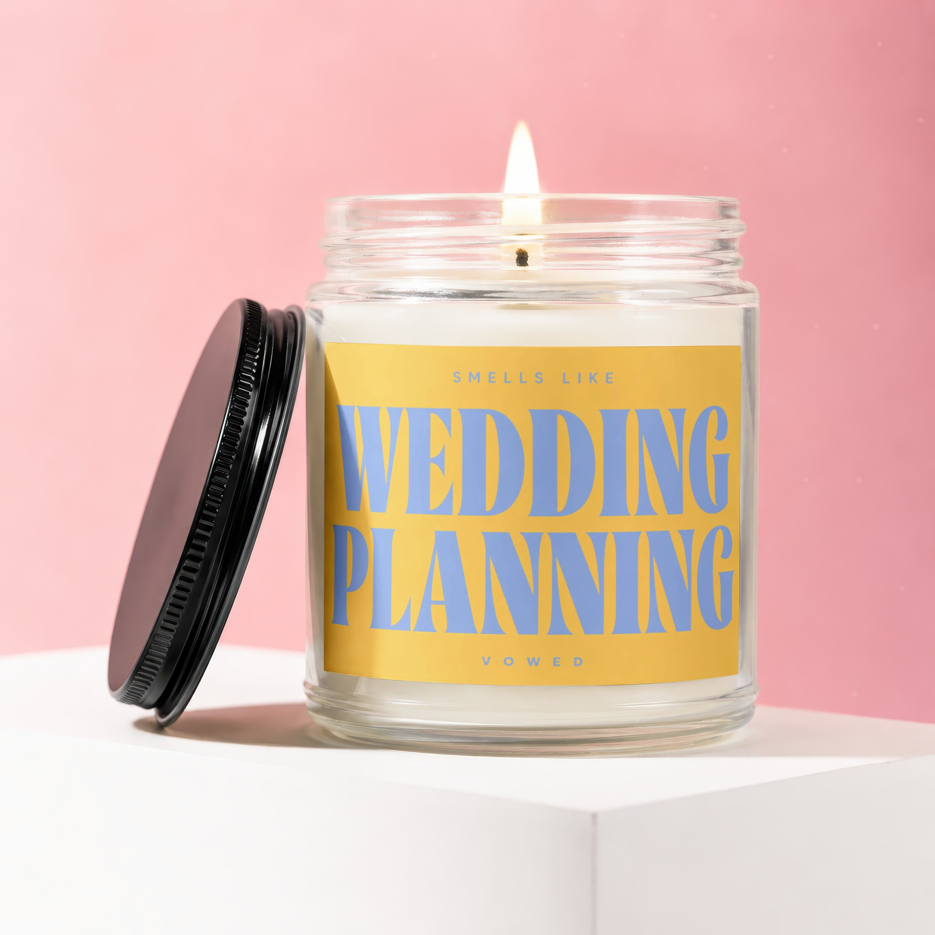 Scented candle with label "Smells Like Wedding Planning Vowed" on pink background