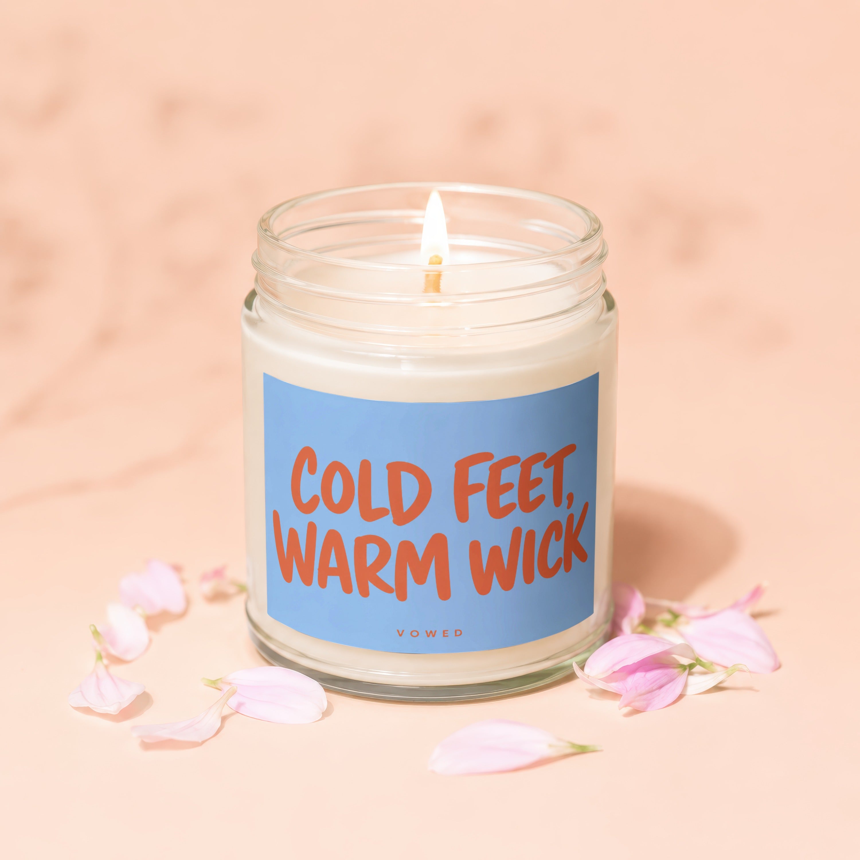 Lit candle in a jar with a blue label that reads "COLD FEET, WARM WICK"