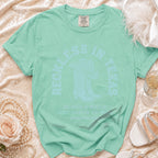 Mint green t-shirt with "Reckless in Texas" and cowboy boots graphic.