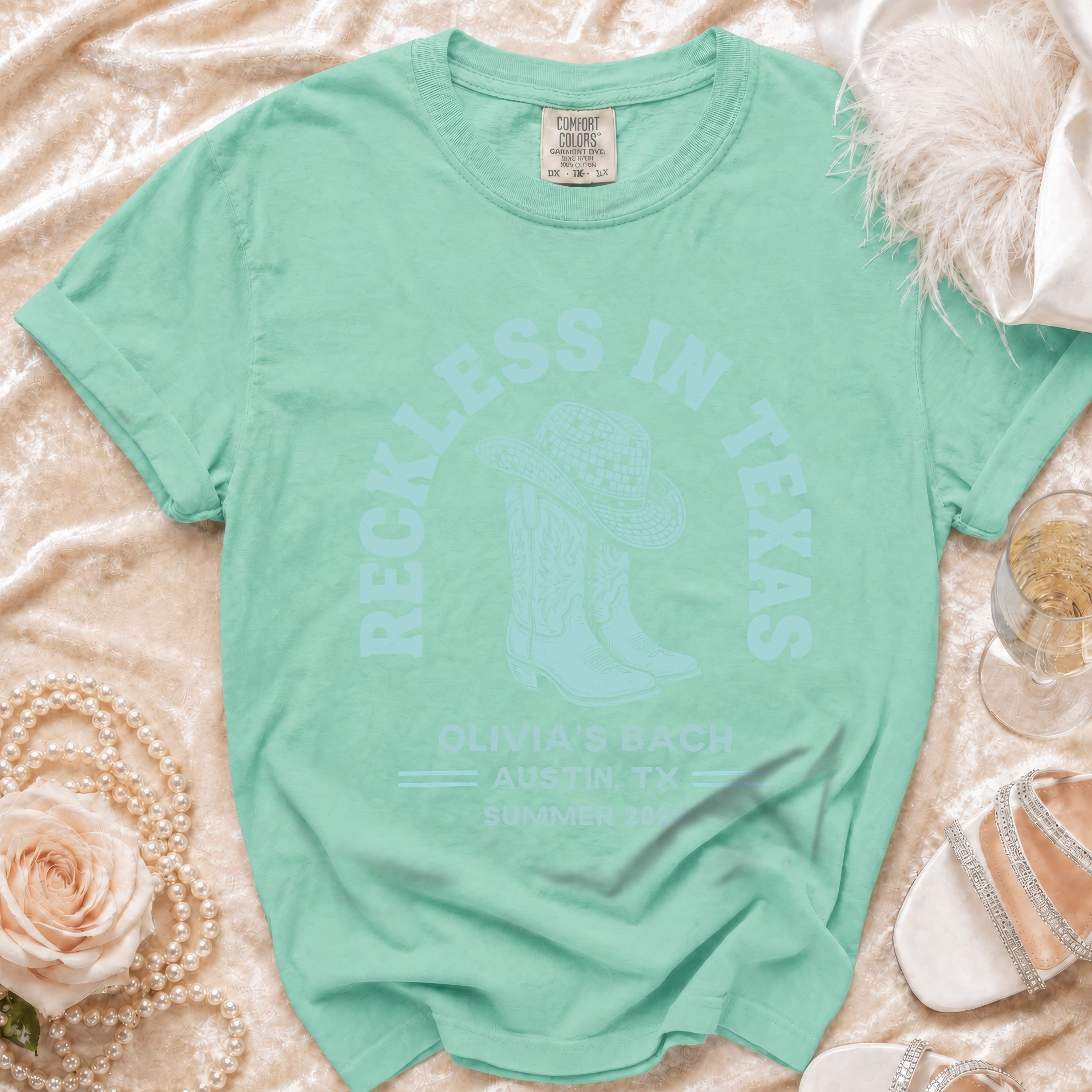 Mint green t-shirt with "Reckless in Texas" and cowboy boots graphic.