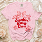 Pink t-shirt with red "Slumber Party Crew" graphic, sleep mask, champagne glass, slippers.