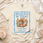 Cream t-shirt with "Reckless in Texas" and "Olivia's Bach" text.