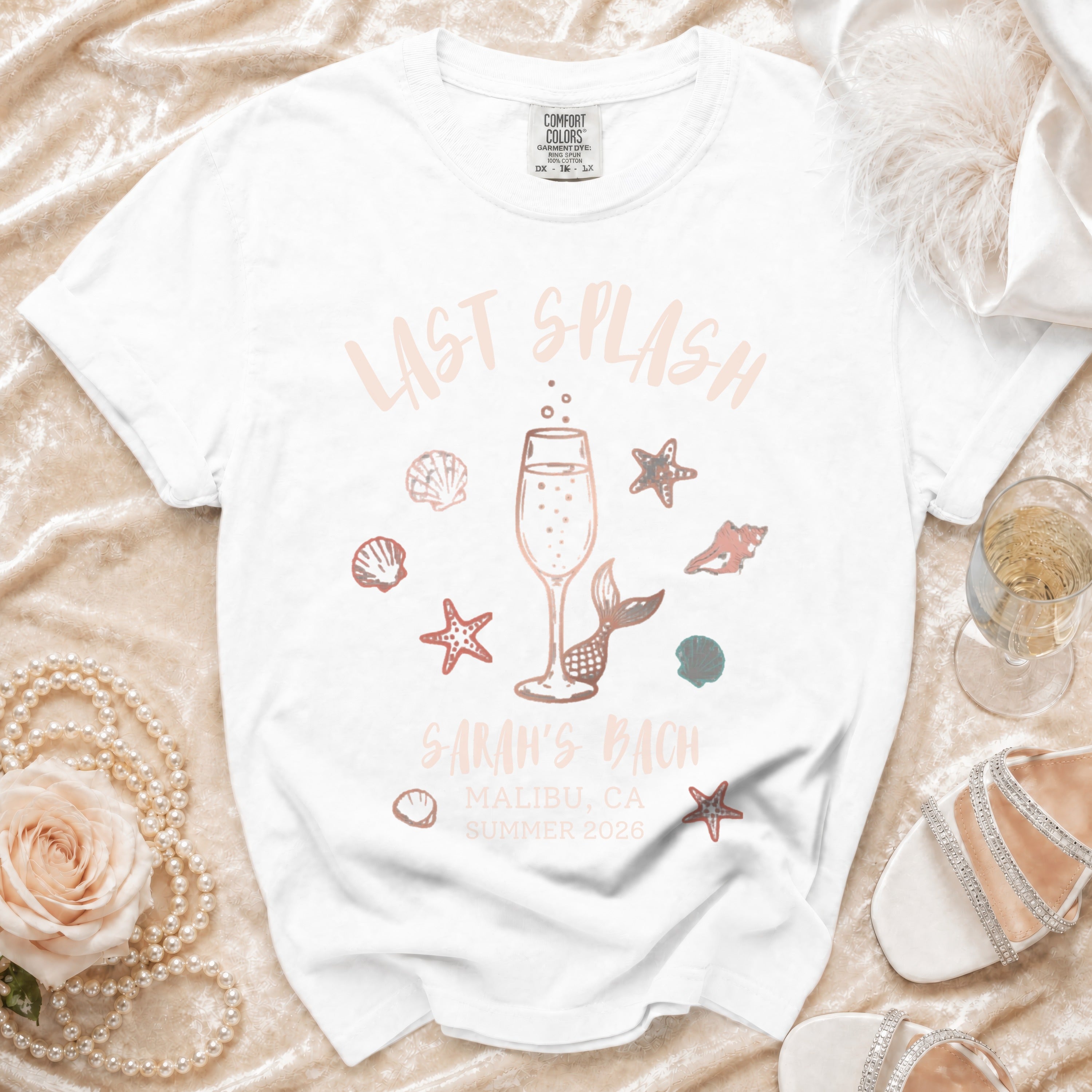 White t-shirt with "Last Splash" and "Sarah's Bach" text and beach graphics.