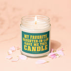 Glass candle with lit wick, text "MY FAVORITE DAUGHTER-IN-LAW GAVE ME THIS CANDLE".