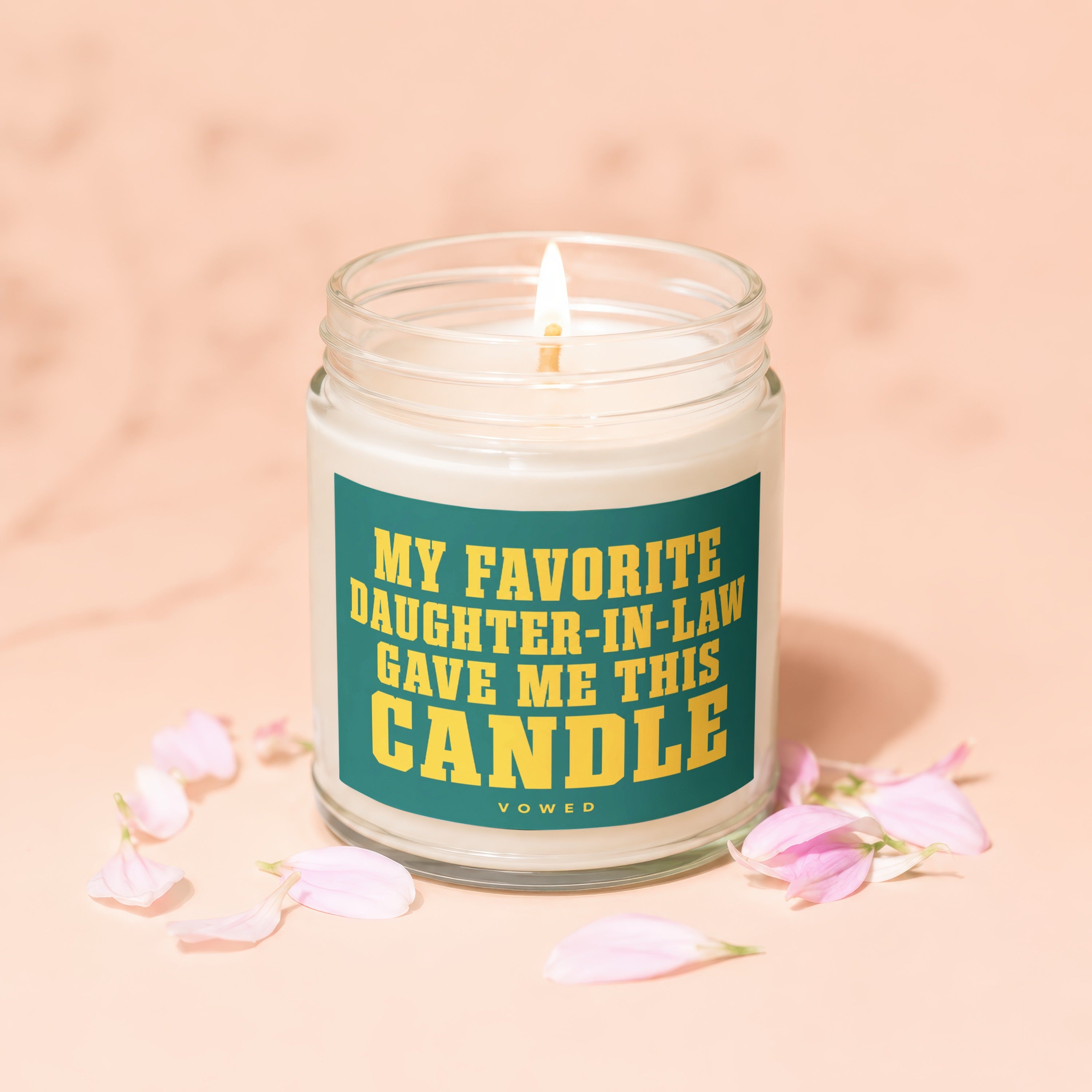 Glass candle with lit wick, text "MY FAVORITE DAUGHTER-IN-LAW GAVE ME THIS CANDLE".