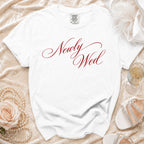 White t-shirt with "Newly Wed" in red script and wedding accessories.