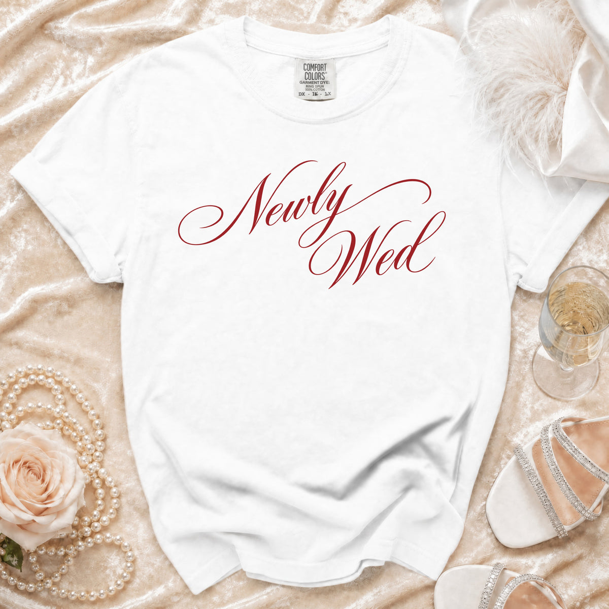 White t-shirt with "Newly Wed" in red script and wedding accessories.