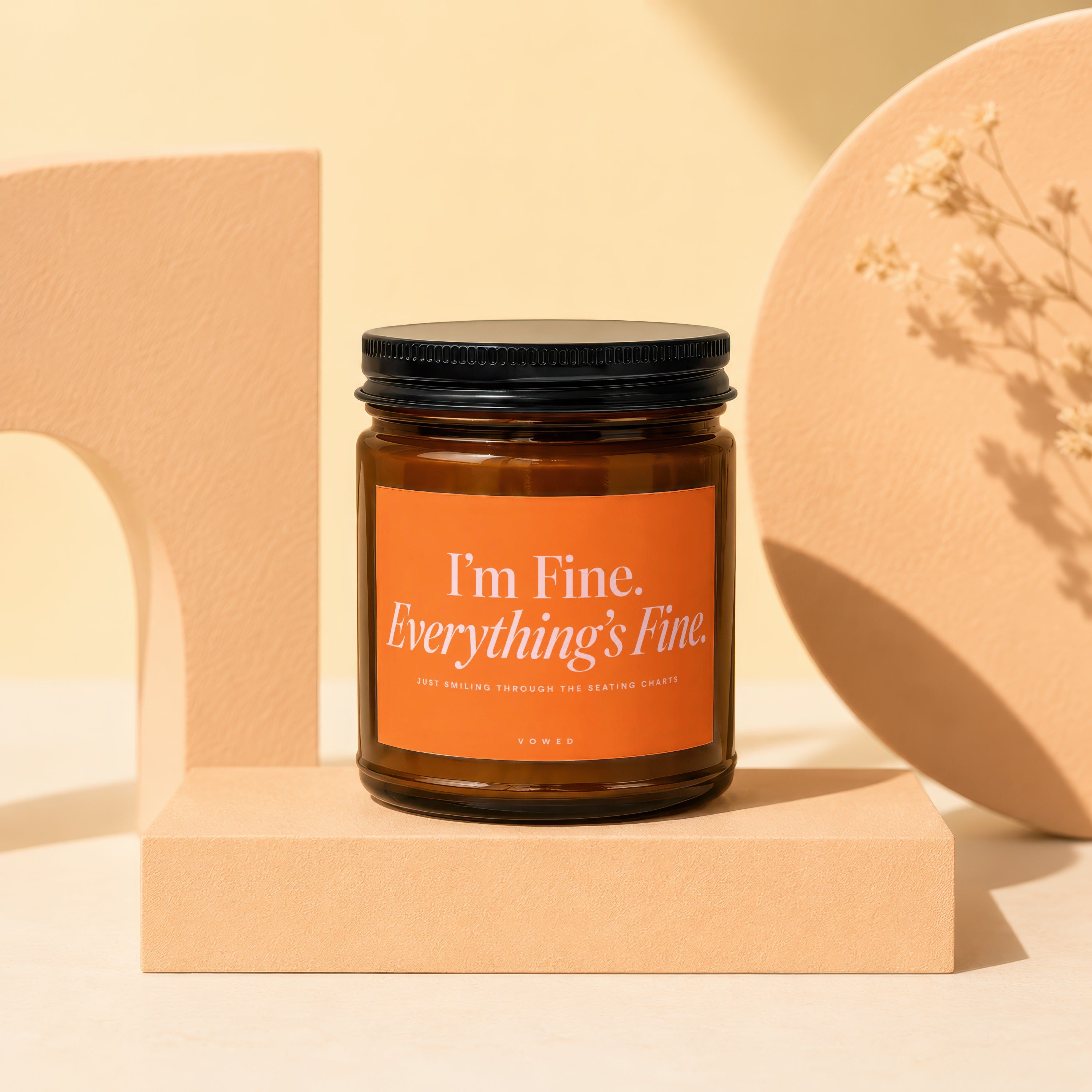 Amber jar candle with orange label reading "I'm Fine. Everything's Fine. JUST SMILING THROUGH THE SEATING CHARTS."