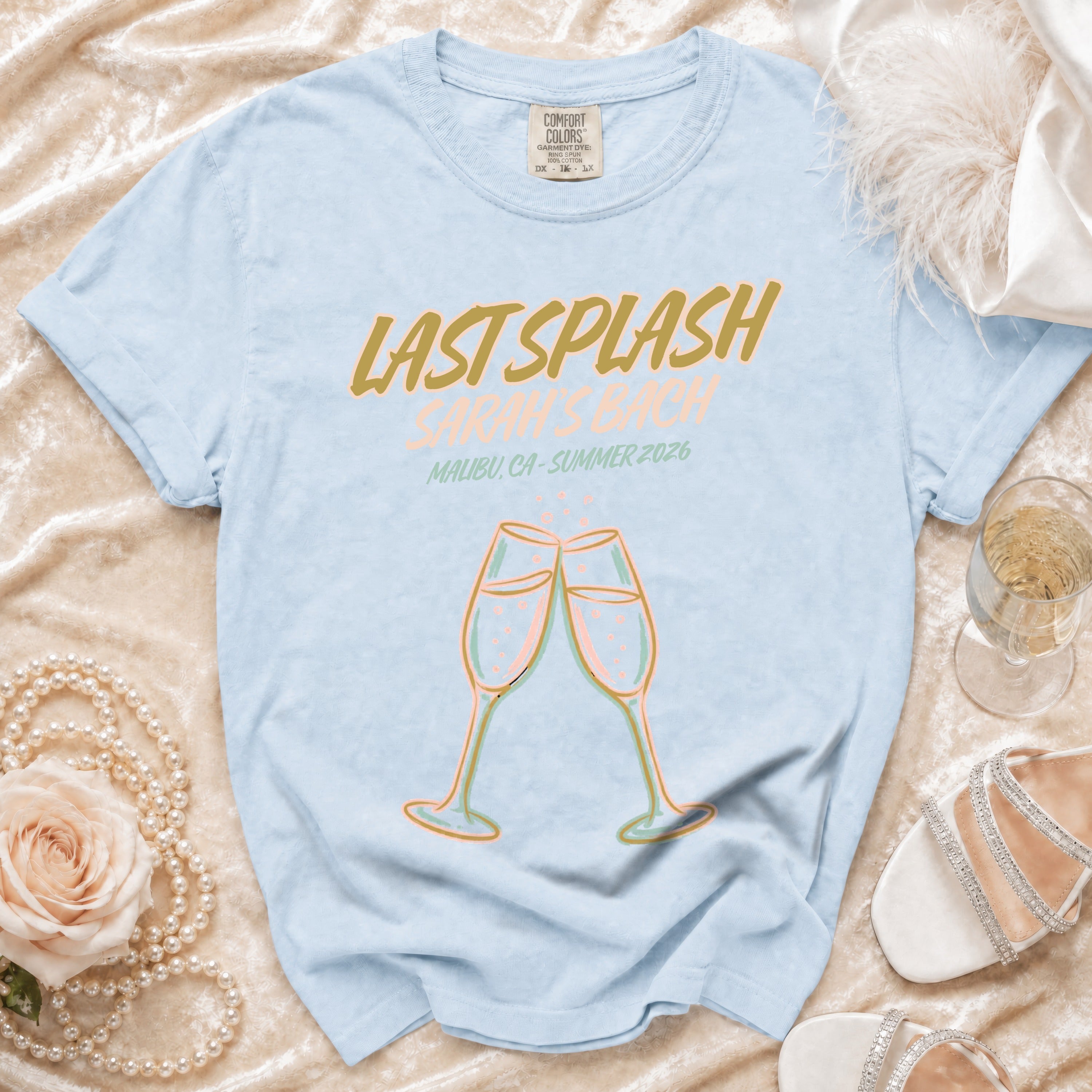 Light blue t-shirt with "Last Splash Malibu, CA - Summer 2026" text and champagne glasses.