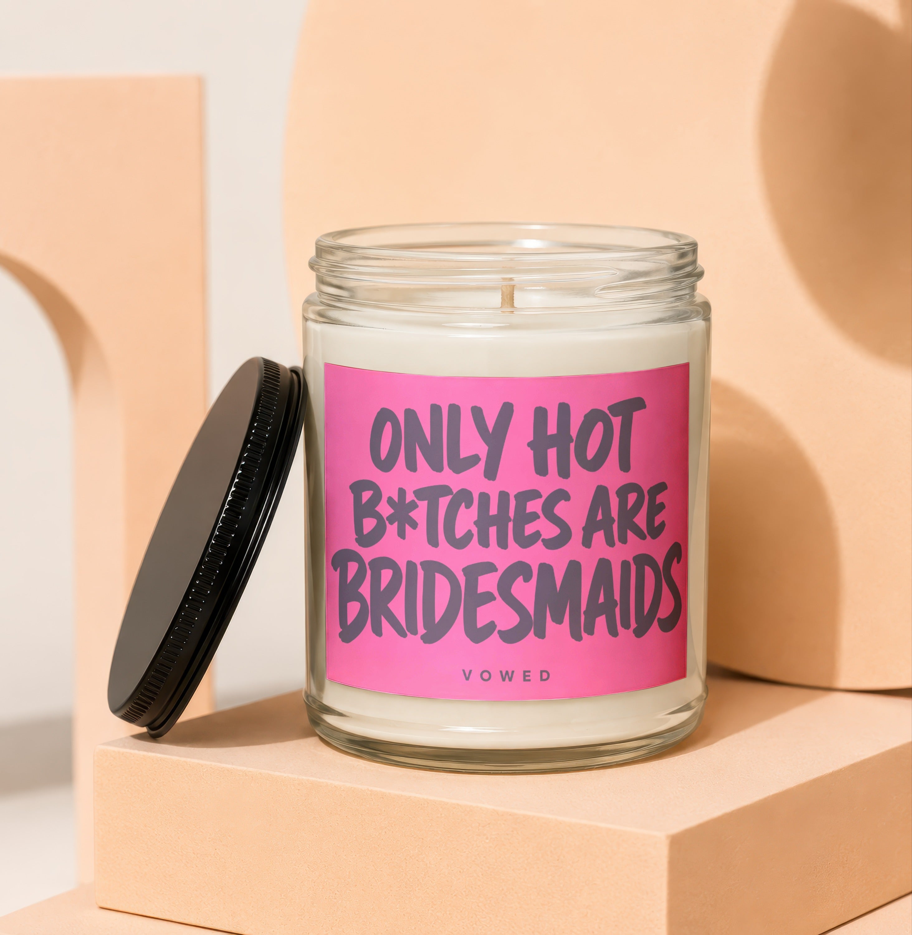 Candle with pink label reading "ONLY HOT B*TCHES ARE BRIDESMAIDS".