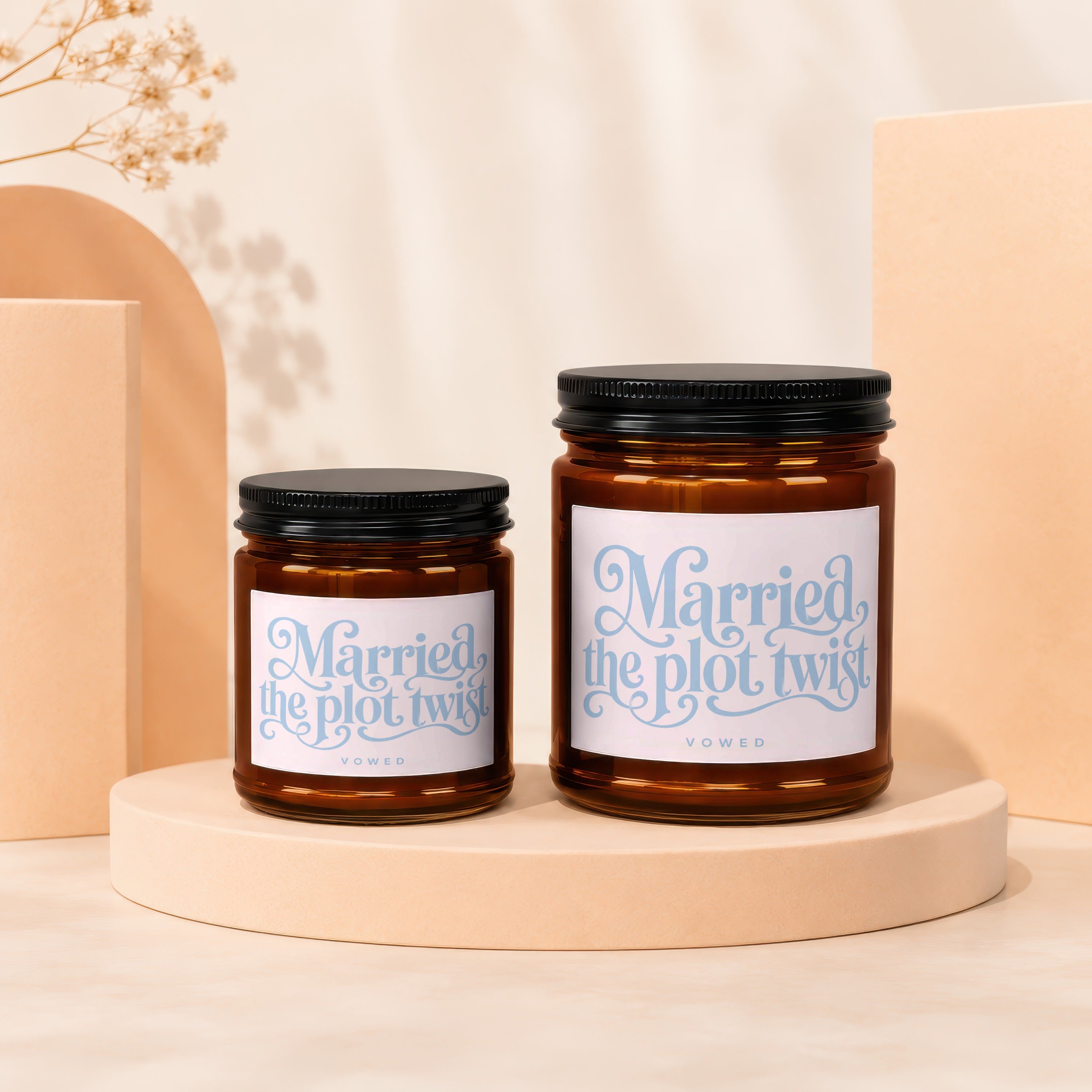Two amber glass candles with black lids, labels read "Married the plot twist."