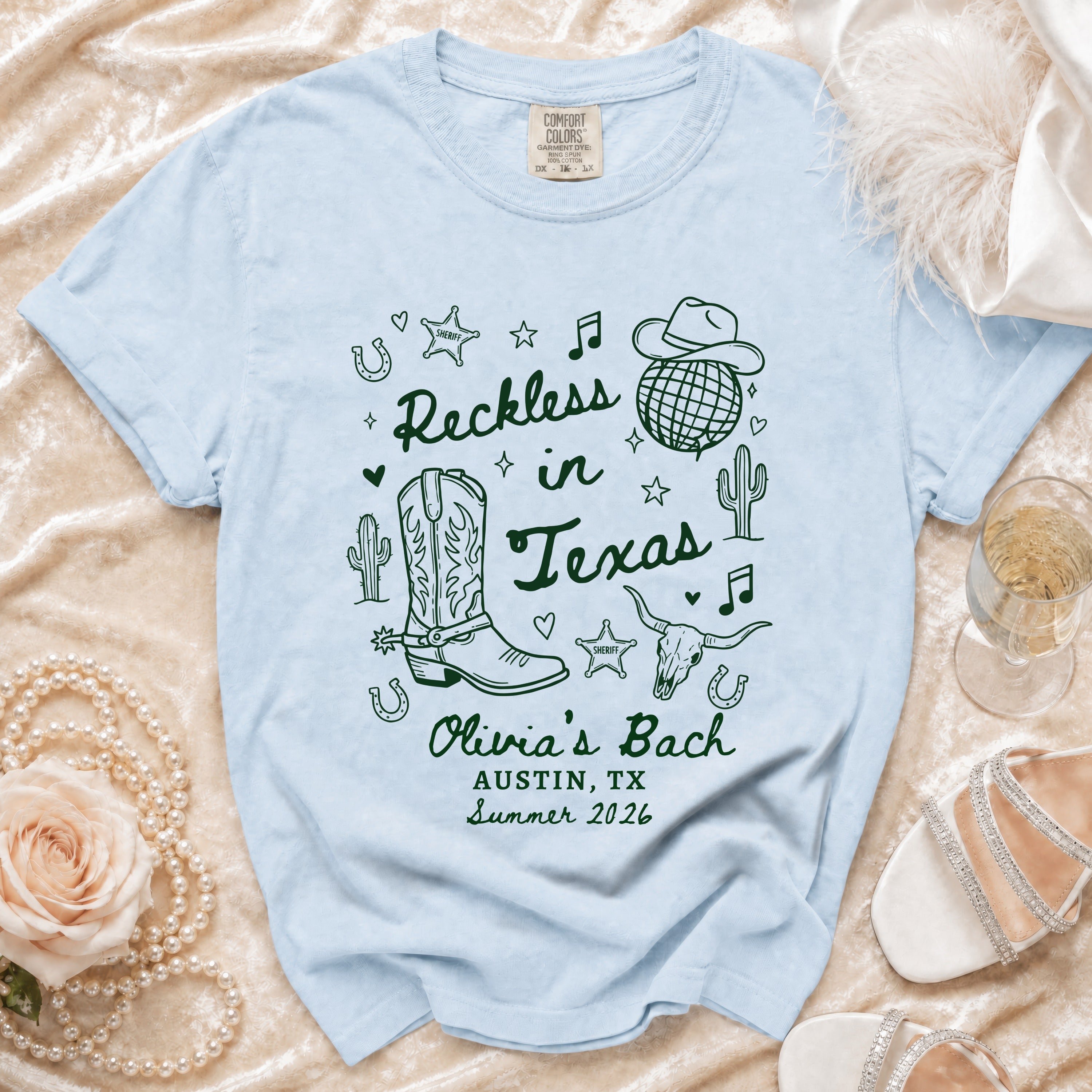 Light blue t-shirt with "Reckless in Texas" and "Olivia's Bach Austin, TX Summer 2026" text.