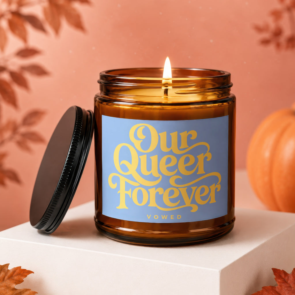 Amber jar candle with "Our Queer Forever Vowed" text on a blue label.