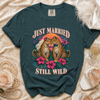 Dark teal t-shirt featuring two leopards in wedding attire with text "JUST MARRIED STILL WILD."