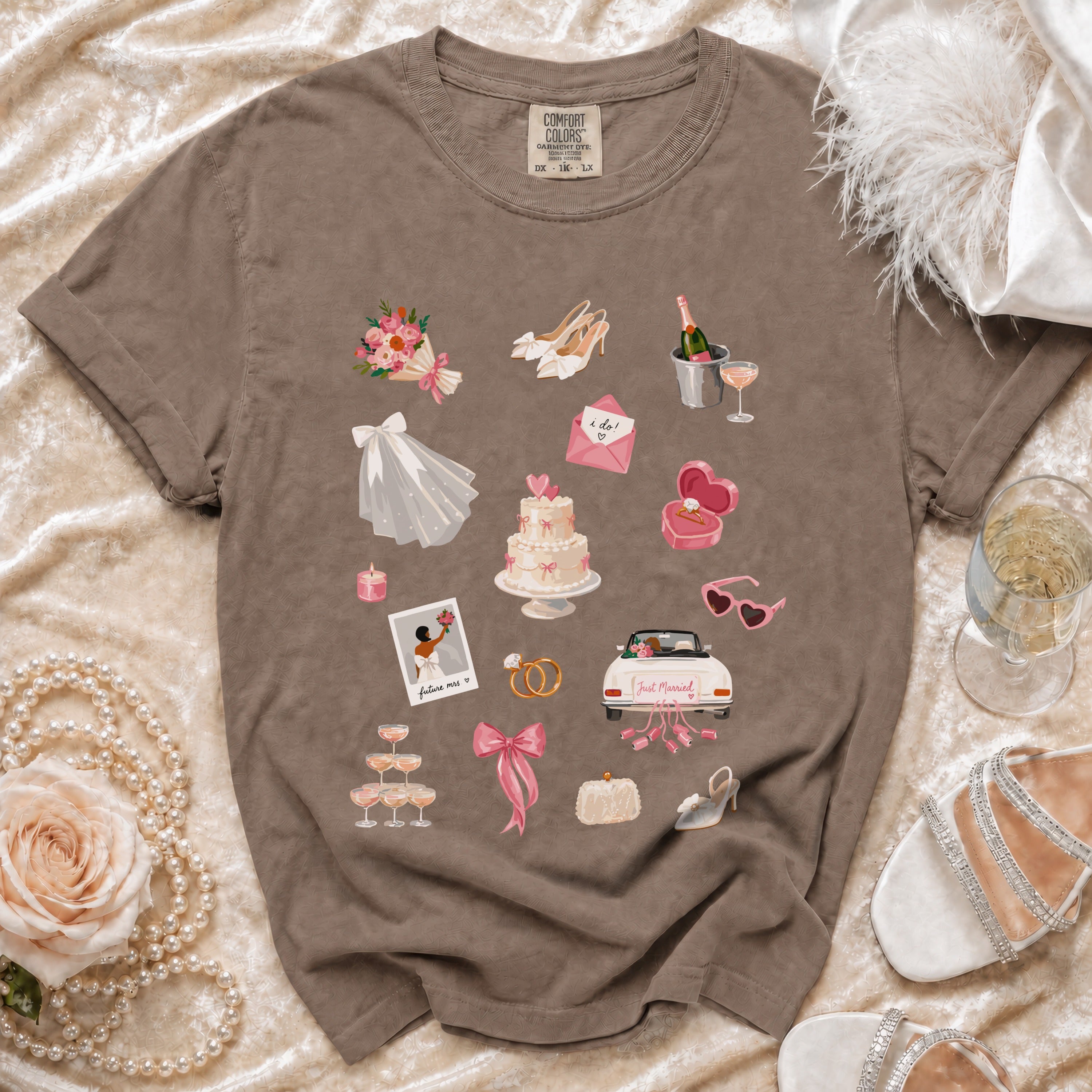 Brown t-shirt with a collage of wedding-themed illustrations, including a cake, rings, and champagne.