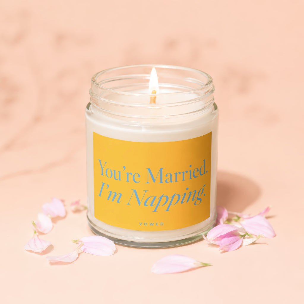 Lit candle in a jar with "You're Married. I'm Napping." text and petals.