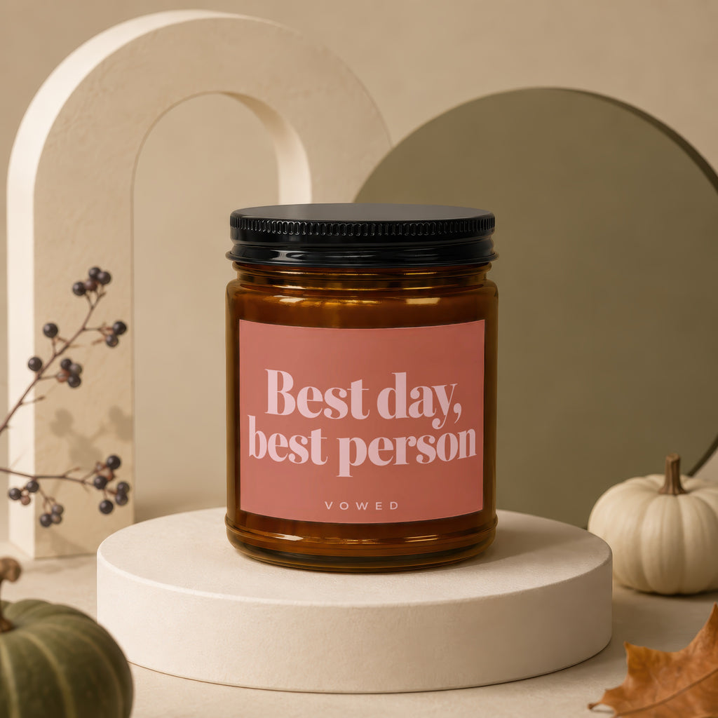 Candle with "Best day, best person" text on a peach label, on a display stand.