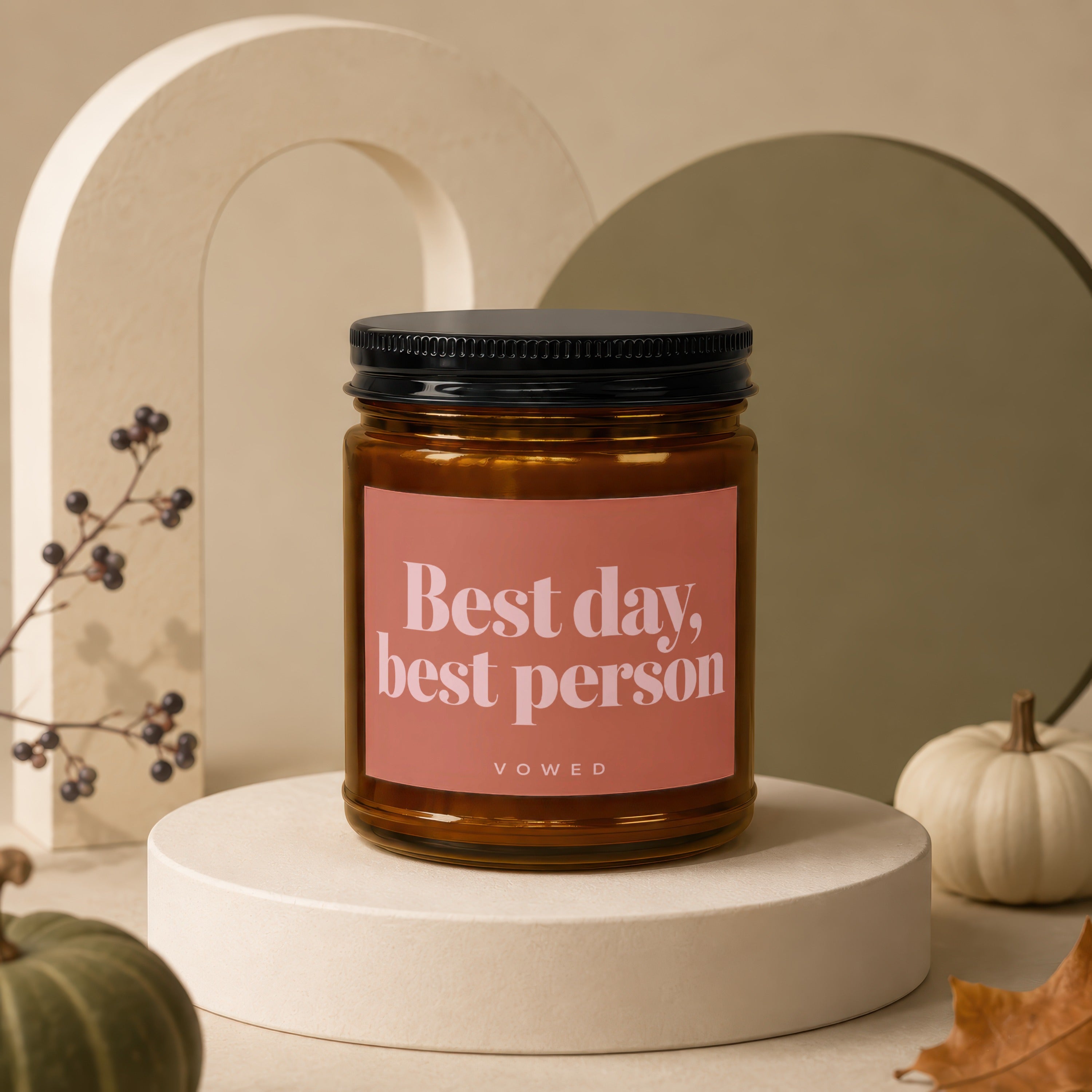 Candle with "Best day, best person" text on a peach label, on a display stand.