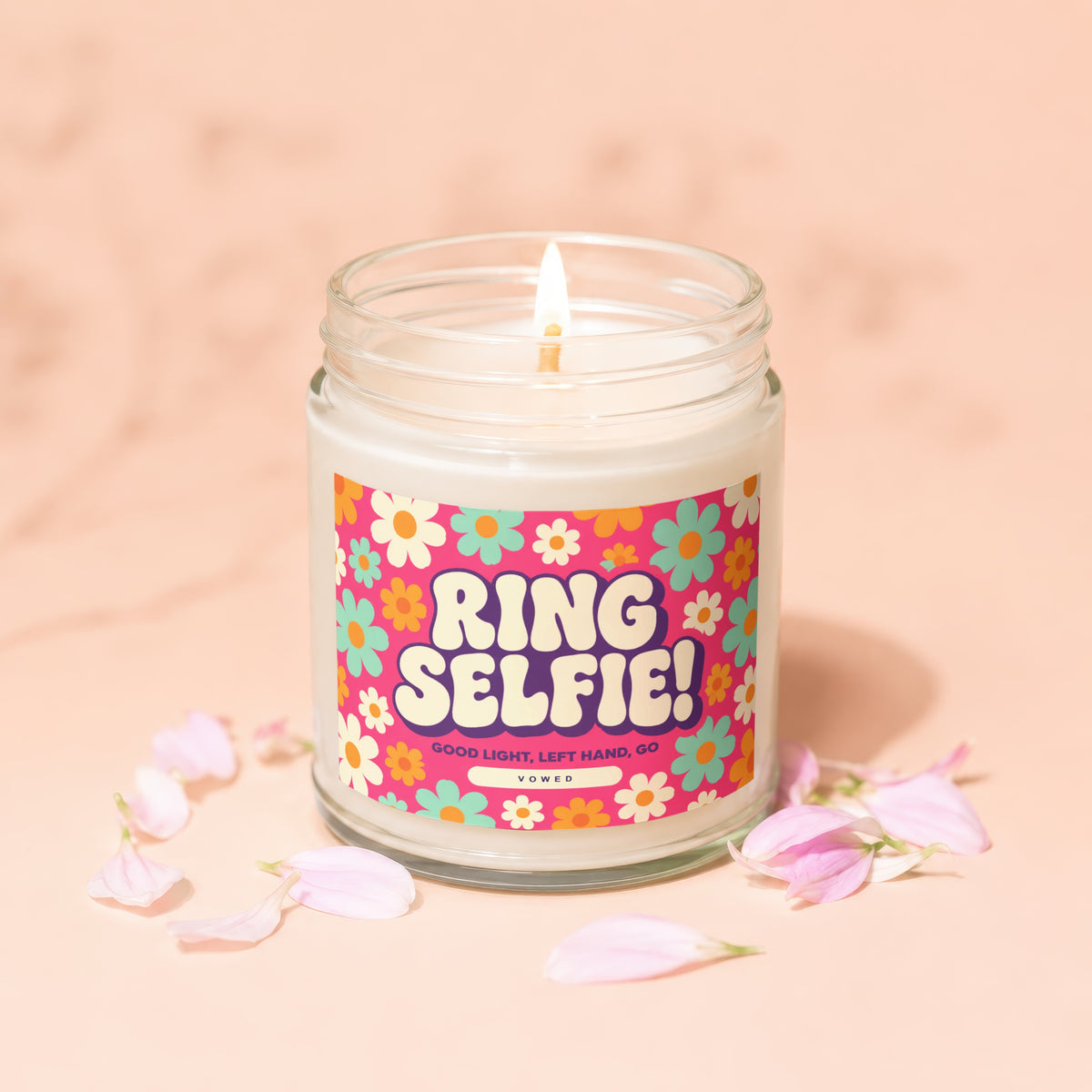 Jar candle with "RING SELFIE!" text and floral design, lit with petals.