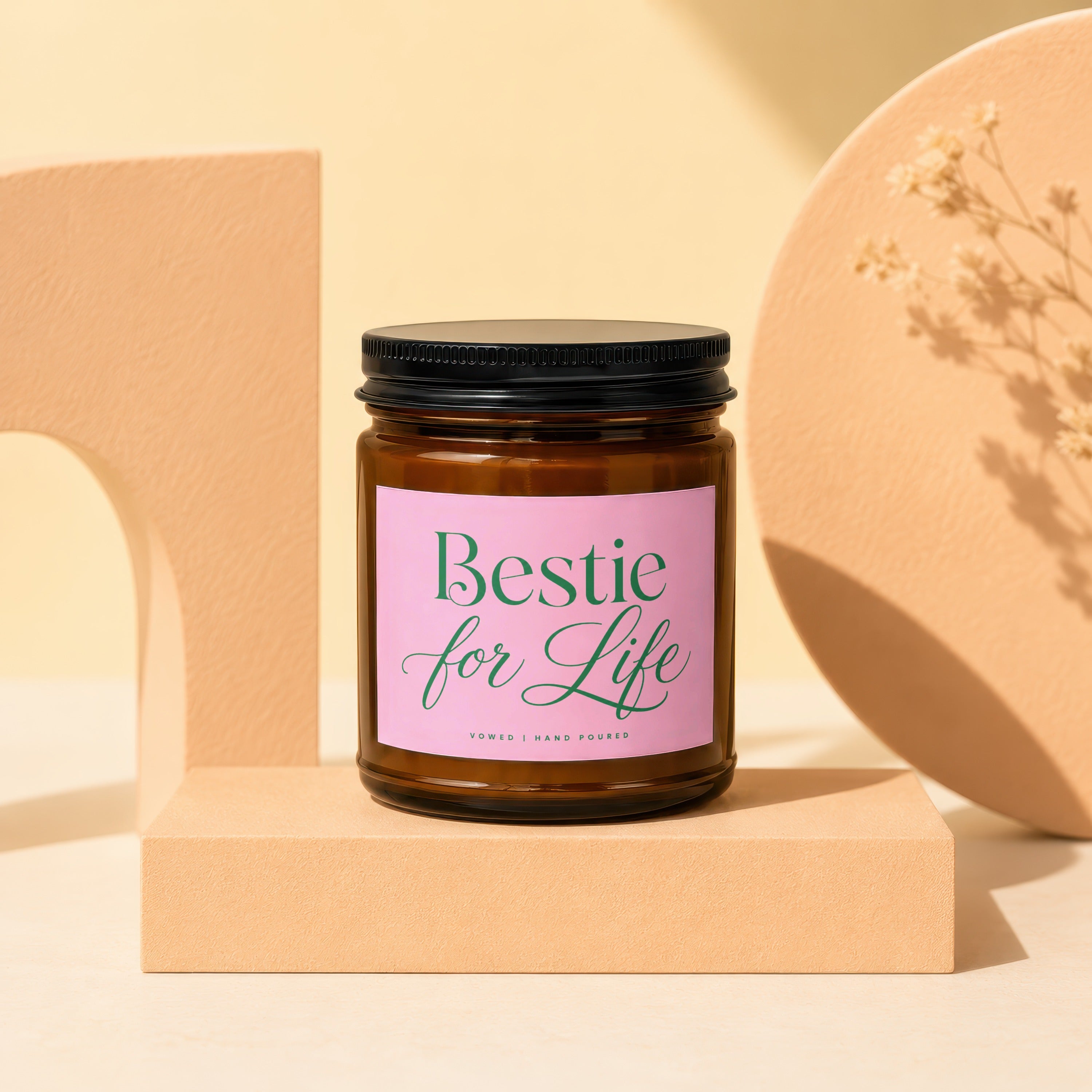 Amber glass candle with "Bestie for Life" pink label and black lid.