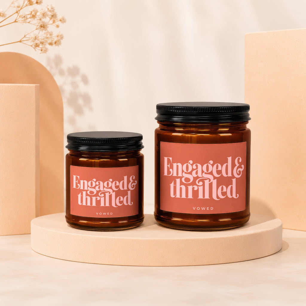 Two amber glass candles with black lids, labeled "Engaged & thrilled".