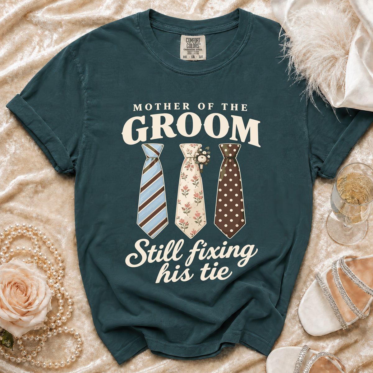 Teal t-shirt with "Mother of the Groom Still fixing his tie" text and three ties.