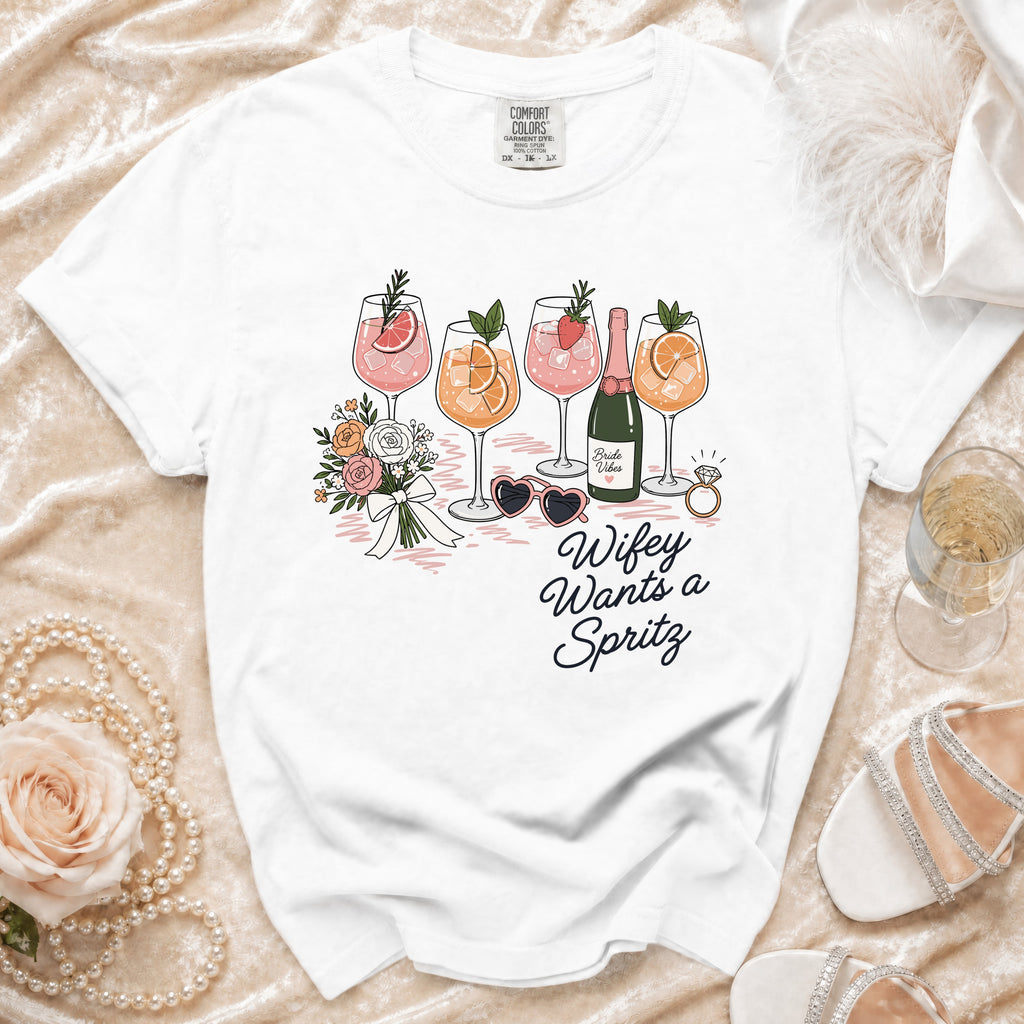 White t-shirt with "Wifey Wants a Spritz" graphic featuring drinks, flowers, and accessories.