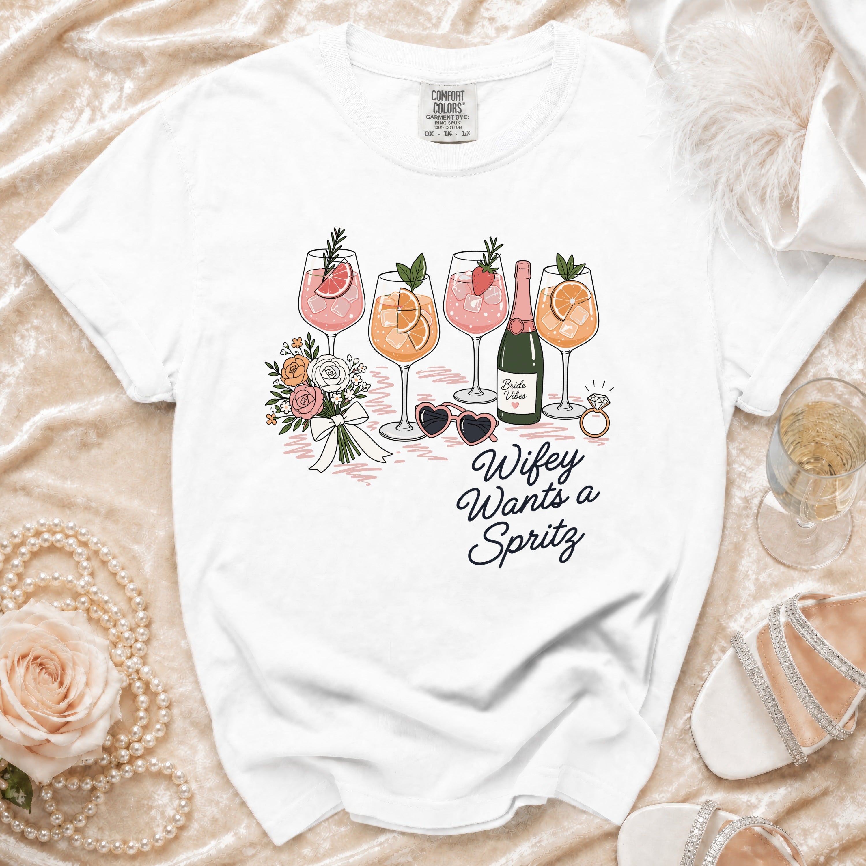 White t-shirt with "Wifey Wants a Spritz" graphic featuring drinks, flowers, and accessories.