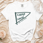 White t-shirt with "Camp Sarah Lake Tahoe 2026" text on a pennant graphic.