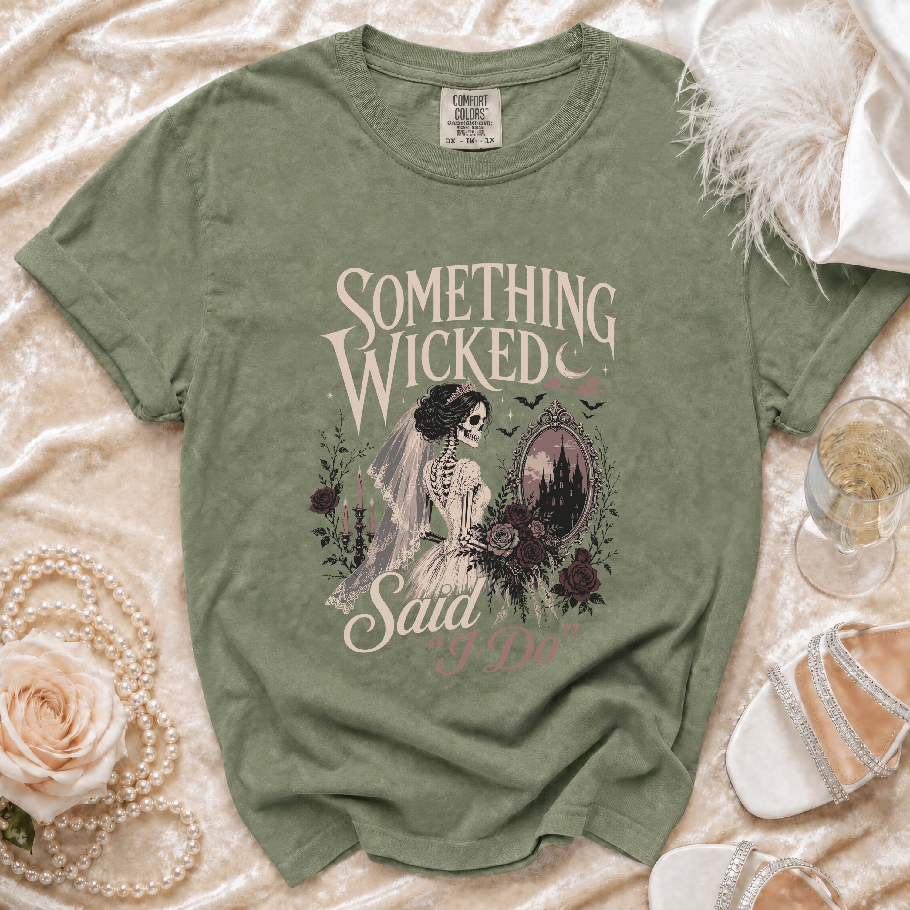 Sage green t-shirt with skeleton bride graphic saying "Something wicked said I do."