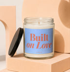 Glass candle with blue label that reads "Built on Love VOWED".