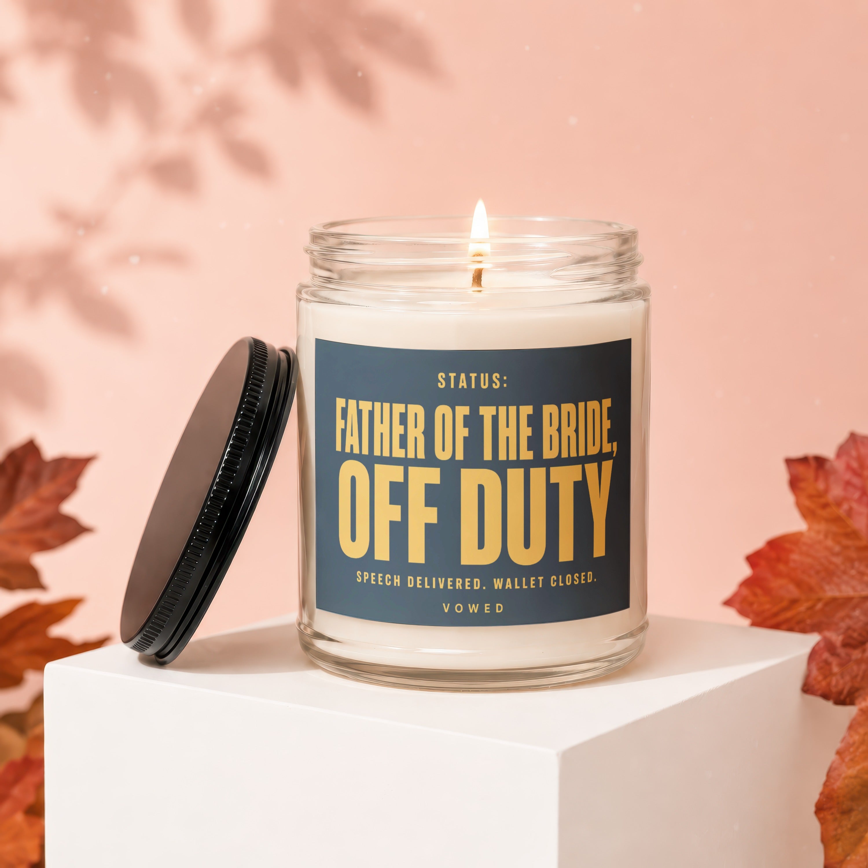 Candle with label "Father of the Bride Off Duty" on a white cube.
